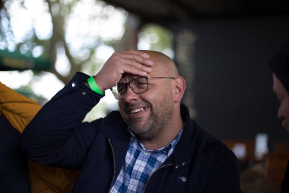 Lächelnder Mann mit Brille, der sich nachdenklich die Stirn hält.